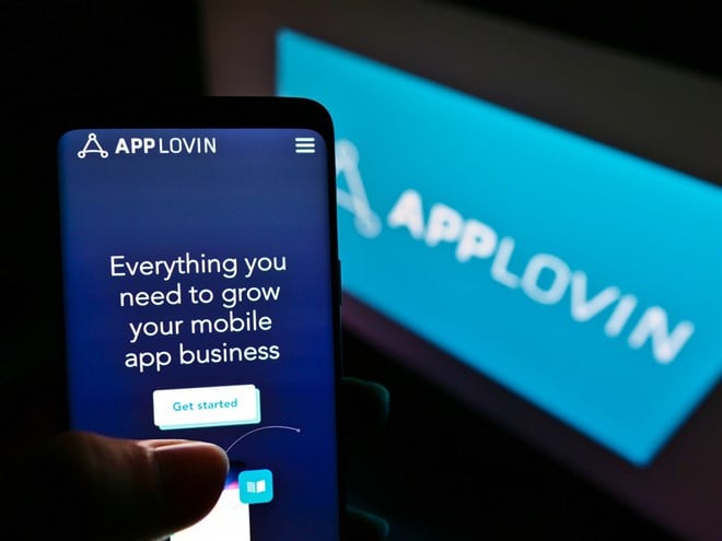 Person holding mobile phone with website of technology company AppLovin Corp. on screen with logo