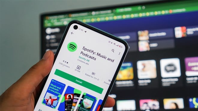 holding smartphones opening spotify app, Spotify is a music service that offers legal streaming music.