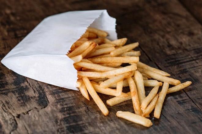French fries potatoes in a paper bag on wood background — Photo