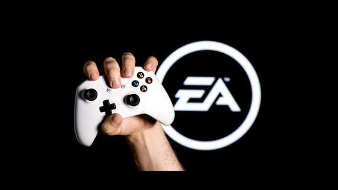 A white gamepad clutched in the hand on the black background with the logo of Electronic Arts