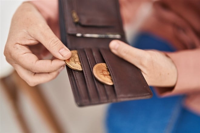 Photo of a person holding bitcoin of leather wallet