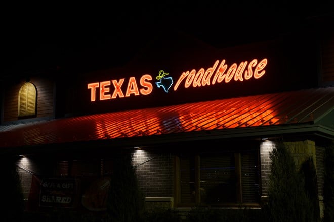 Texas Roadhouse restaurant exterior and trademark logo at night.