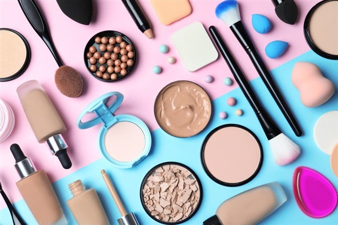 Flat lay composition with skin foundation, powder and beauty accessories on color background - stock image