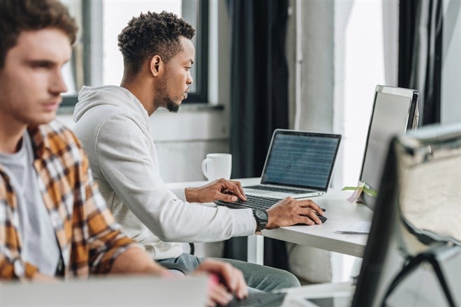 Selective focus of two multicultural programmers working together in office - stock image