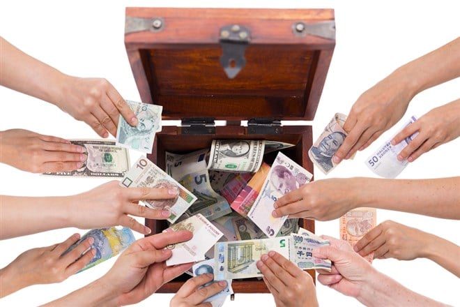 Phto of different hands putting money into one box; concept photo of pooled investment vehicles.