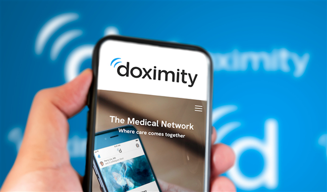 Doximity company website on a phone screen. Blue background with Doximity logo blurred in the background