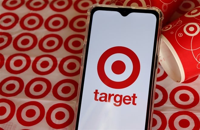 Target Store logo on smartphone screen with Target cups and shopping bag in the background.