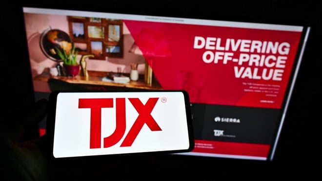 Person holding smartphone with logo of US department store company The TJX Companies Inc. on screen in front of website