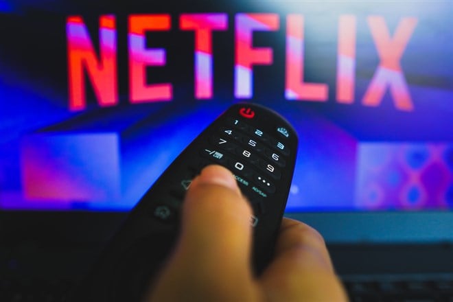 Netflix a close-up of a hand holding a TV remote control