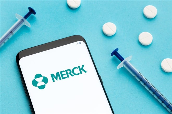 Galicia, Spain; June 8, 2020 : Smart phone showing Merck logo on screen and pills and syringe on blue background