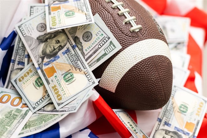 Money and football on american flag background, closeup. Concept of sports bet.