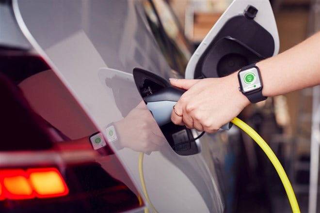 Close Up Of Hand Attaching Power Cable To Environmentally Friendly Zero Emission Electric Car - stock image