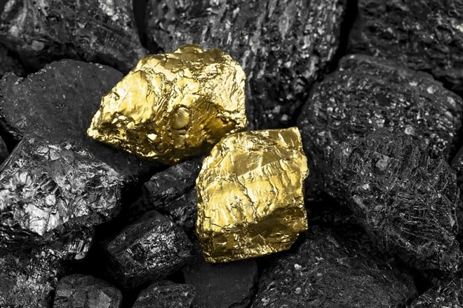 Shiny golden nuggets on black coals, top view.