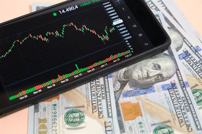 Stock exchange chart on smartphone screen and hundred dollar bills on beige background - stock image