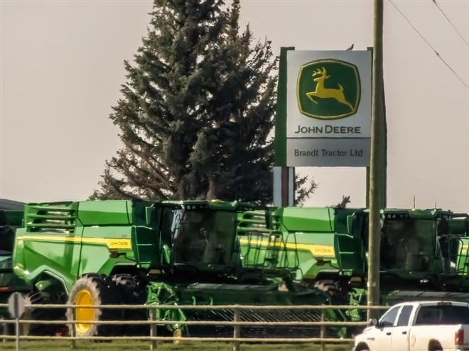 Alberta, Canada. Aug 24, 2024. A John Deere dealership sign stands prominently above a row of green agricultural machinery. — Stock Editorial Photography