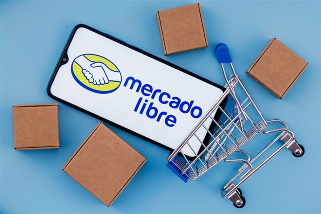 Photo of a smartphone with the MercadoLibre logo inside a small shopping cart surrounded by brown boxes; e-commerce