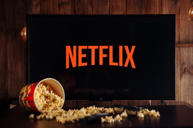 Photo of a Netflix logo on a TV screen, a container of spilled popcorn across the table in front of it.