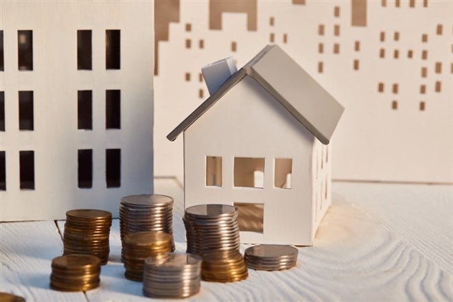 Houses models on white wooden table with coins, real estate concept - stock image