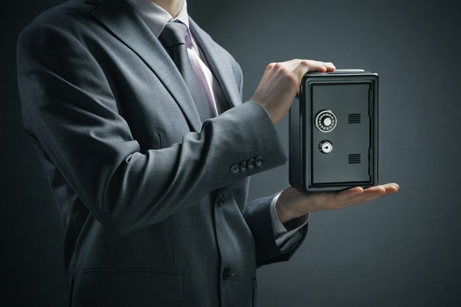 Photo of a man in a suit holding a safe; symbolizing a safe investment.