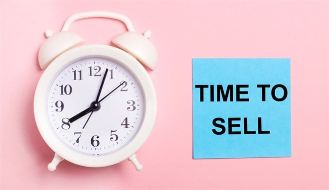 Photo of a clock and a post it that says "Time to Sell" against a pink background