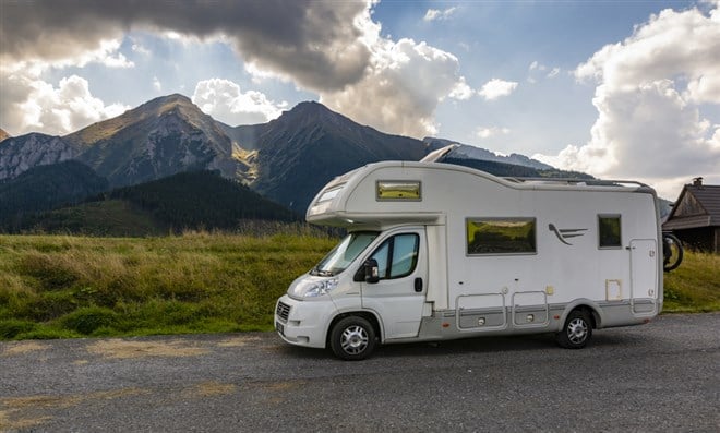 Photo of an RV against a mountainous background.