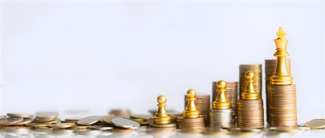 Photo of an increasing stack of coins with rook chess pieces on most, and a King on the biggest one 