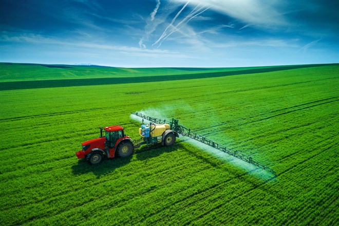 Aerial view of farming tractor plowing and spraying on field — Photo