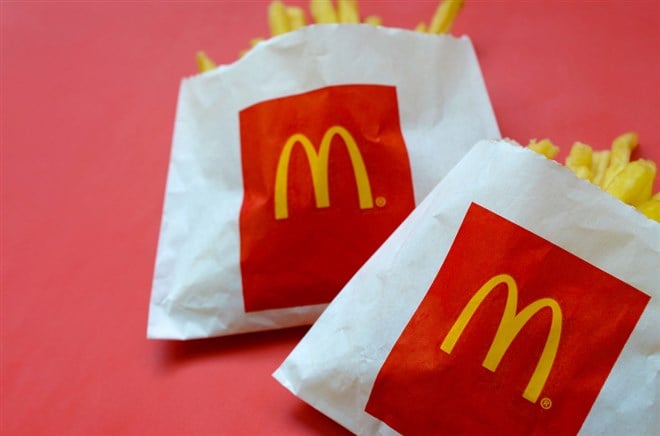 McDonald's French fries in small paperbag on bright red background - Stock Editorial Photography