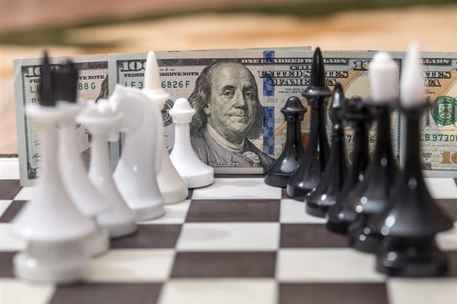 US dollars and chess figures on chessboard