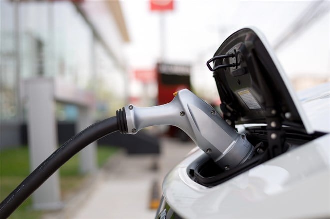 Electric car plugged in with charging station to recharge battery 