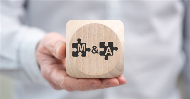 Hand holding a wooden cube with symbol of m&a concept