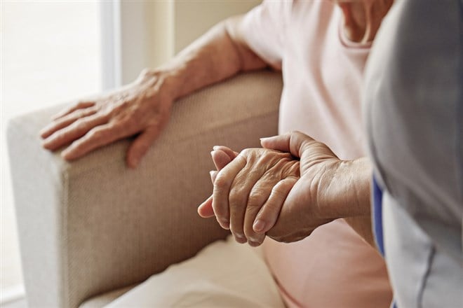 Mature female in elderly care facility gets help from hospital personnel nurse. Senior woman with aged wrinkled skin & care giver, hands close up. Grand mother everyday life. Background, copy space. — Photo