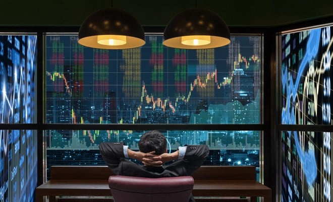 Photo of a businessman surrounded by stock market screens.