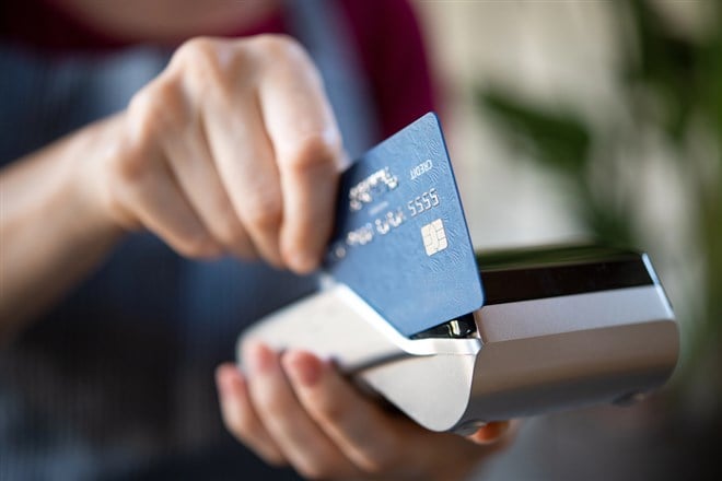 Close up hands of waitress holding credit card machine terminal and swiping debit card to pay the bill. Payment with a credit card through terminal at restaurant or cafeteria. — Photo