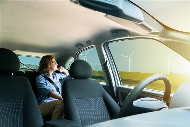 Woman passenger sitting in the backseat and looking out the window when her self-driving car rides on the highway. — Photo