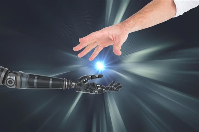 Photo illustrating the connection between human and robot hand against silver background