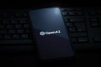 Image of OpenAI on a phone on a computer keyboard; learn about how to buy openai stock
