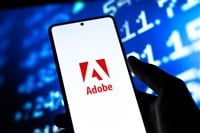 Adobe logo on smartphone screen with stock market background