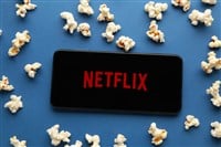 Smartphone with Netflix logo and popcorn on blue background