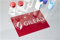 Vials of liquid on a white table and the logo of Gilead Sciences