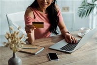 Cropped view of asian woman holding credit card near laptop and smartphone