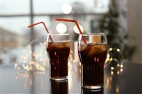 Glasses of cold cola and fairy lights on table - stock image