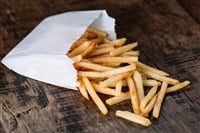 French fries potatoes in a paper bag on wood background — Photo