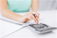 Photo of a woman inputing information into a calculator.