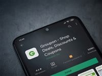 Groupon app play store page on the display of a black mobile smartphone on dark marble stone background