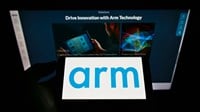 Person holding mobile phone with logo of British semiconductor company Arm Ltd. on screen in front of business webpage. 