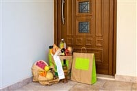 A grocery bag under the door of the house.Food delivery to the door in craft bags. Delivery of groceries home