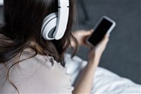 Cropped view of girl listening music with headphones and smartphone