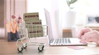 Cartons with KOHLS logo in shopping trolley near laptop. Editorial online store order related 3D rendering 