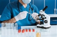 Cropped view of biologist in medical mask and latex gloves holding syringe near microscope — Photo